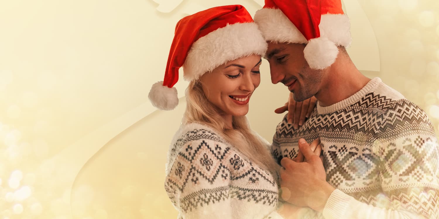 Giovane coppia innamorata di cappelli di Babbo Natale che ballano insieme